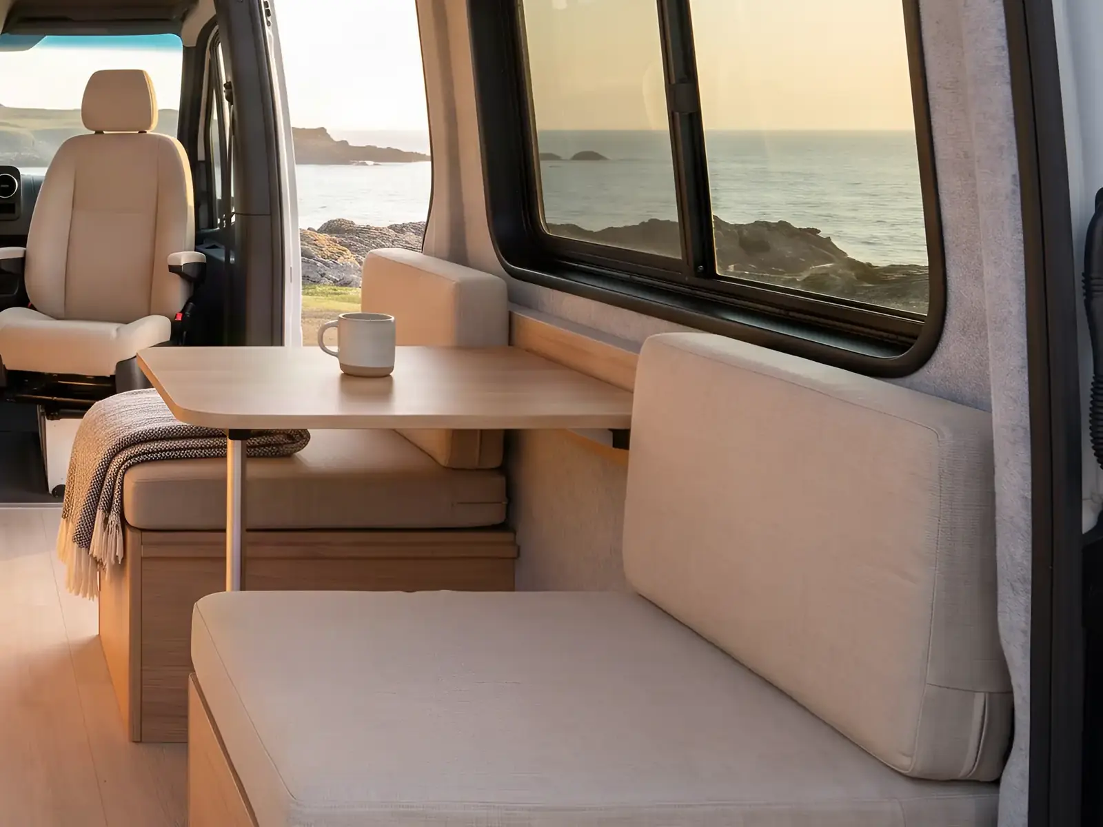 Banquette et table dans un fourgon aménagé, fenêtre sur la mer