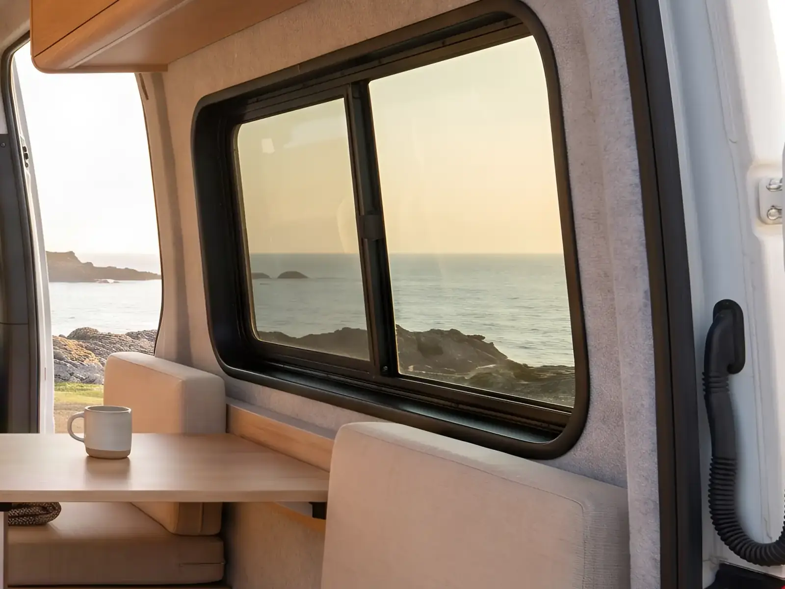 Fourgon aménagé ouvert sur la mer, banquette et fenêtre